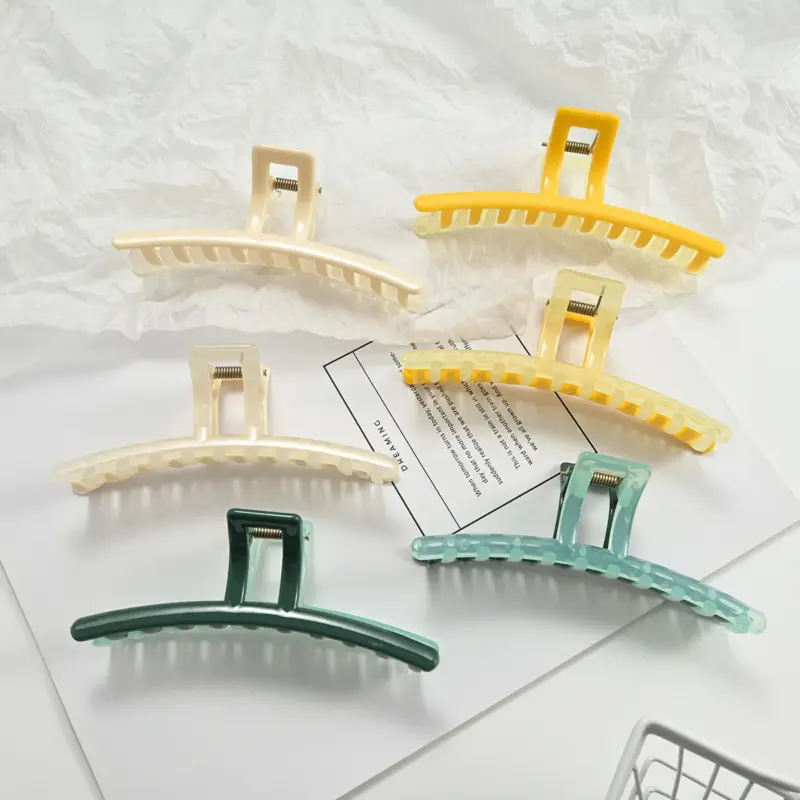 Six two-tone translucent jelly oversized curved shark hair claw clips in fresh pastel shades laid on white paper